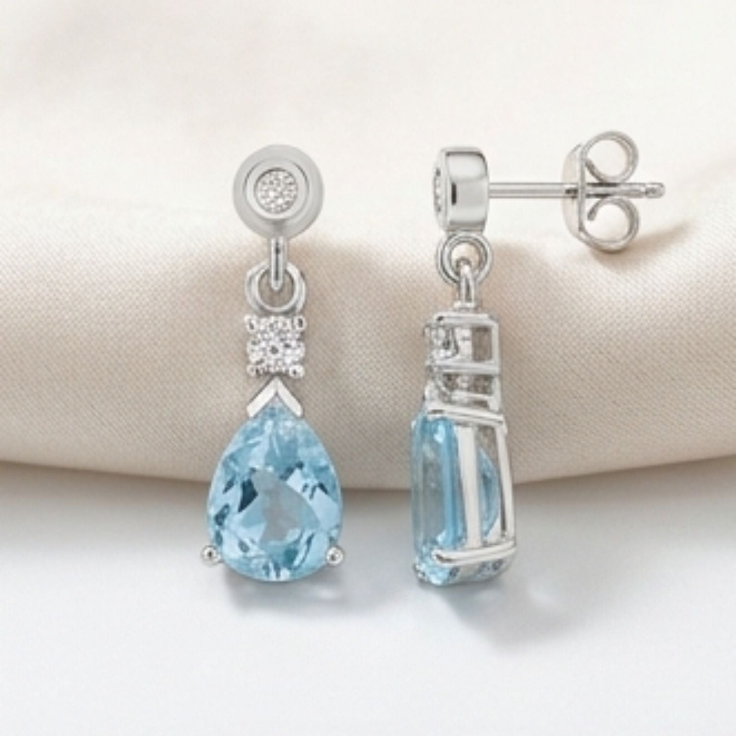 Pear-shaped aquamarine drop earrings in 18k white gold and yellow gold settings.on display